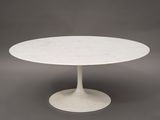 une table en marbre blanc avec un piètement circulaire sur fond gris