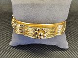 un gros plan d'un bracelet en or posé sur un oreiller