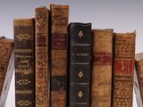 several old books are stacked on top of each other on a shelf