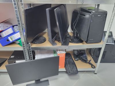 many computer monitors and keyboards on the shelves in the room