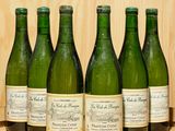 six bouteilles de vin sont alignées sur un tonneau en bois