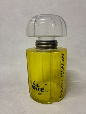 un flacon de parfum jaune posé sur une surface blanche