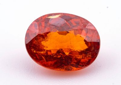 un gros plan d'un saphir orange de forme ovale posé sur une surface blanche