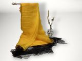 a yellow scarf hanging on a clothes rack next to a vase