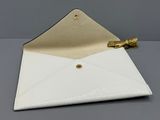 enveloppe en cuir blanc avec un fermoir doré sur un fond gris