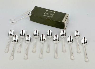 six silver plated spoons and a box of silverware on a white surface