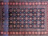 an antique persian rug with a red and blue design on a black ground