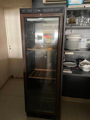 un réfrigérateur à porte vitrée dans une cuisine où de la vaisselle est posée sur le plan de travail
