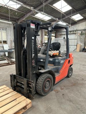a forklift in a warehouse with a pallet in the foreground