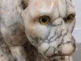 a marble statue of a cat with yellow eyes