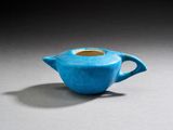 théière en céramique bleue avec une anse, posée sur un fond gris
