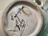 a white vase with writing on it sitting on a green tray