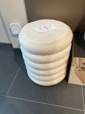 un tabouret blanc posé à côté des toilettes dans une salle de bains