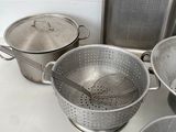 several stainless steel pots and pans are lined up on a counter