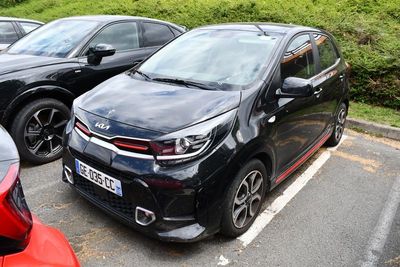 des voitures garées sur un parking devant des buissons et des arbres