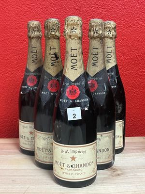 Six bouteilles de champagne sont alignées sur une table en bois.