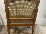 an old wooden chair with wicker seat on a carpeted floor
