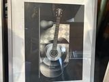 a picture of a guitar in a picture frame in a window