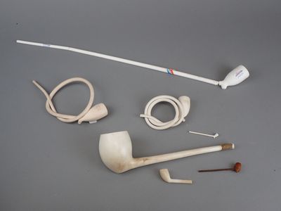 une pipe, un porte-pipe, une pipe et un porte-pipe posés sur une table