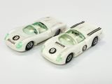 deux voitures jouets assises l'une à côté de l'autre sur une surface blanche