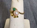 une bague ornée d'une perle et d'une pierre verte
