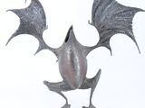 une statue en métal représentant une chauve-souris aux ailes déployées