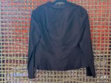 the back of a black jacket hanging on a wicker wall