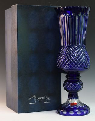 un vase en verre violet posé à côté d'une boîte bleue sur une surface blanche