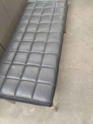 a black leather bench that is in the corner of a room
