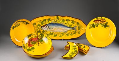 a yellow plate with a fish on it next to other plates and bowls
