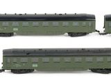 six green train cars are lined up on a white surface