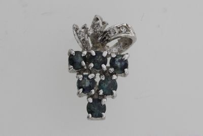 un gros plan d'un pendentif en forme de diamant bleu et blanc posé sur une surface blanche