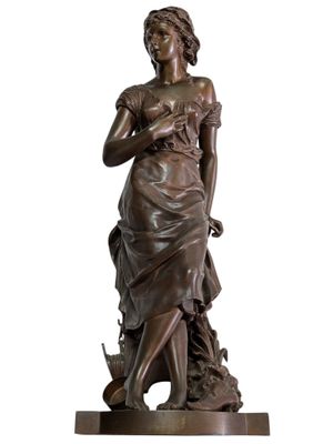 bronze statue of a woman holding a bird on a pedestal