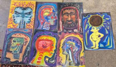 Plusieurs tableaux de différentes couleurs sont posés par terre, les uns à côté des autres.