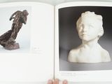 someone is holding a book open to a picture of a statue