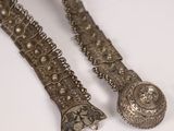une paire de bracelets anciens en argent posés sur une surface blanche, sur fond blanc