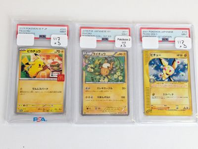 trois cartes Pokémon sont dans des pochettes en plastique posées sur une surface blanche