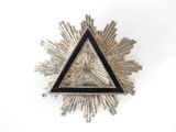 broche en forme de triangle, argentée et noire, ornée d'un motif en forme d'étoile rayonnante au centre