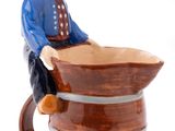 une figurine représentant un homme assis sur un tonneau