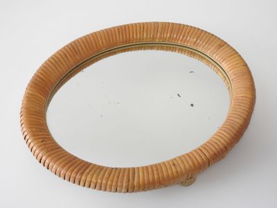 a round mirror with a wooden frame on a white surface