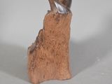 a small statue of a bird sitting on top of a piece of wood