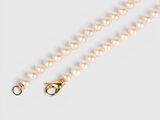 a close up of a white pearl necklace with a gold clasp