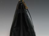 a close up of a black purse on a white surface