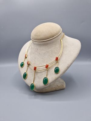 un collier composé de perles vertes et rouges, présenté sur un mannequin