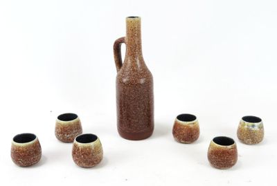 a brown vase and six small cups in front of it