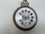 une montre de poche sur laquelle figure une horloge, posée sur une table