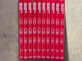 six livres rouges posés sur une surface en béton, sur fond blanc