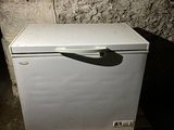 a small white refrigerator sitting on a pallet in a room