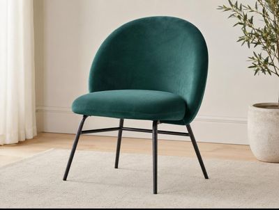 the green chair is next to a potted plant in a white room