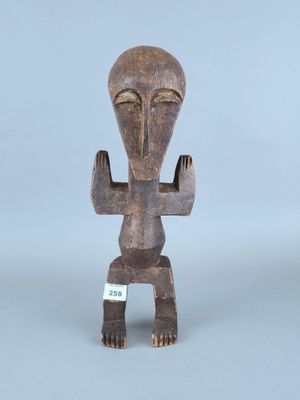 un gros plan sur une statue en bois représentant une personne, sur fond gris